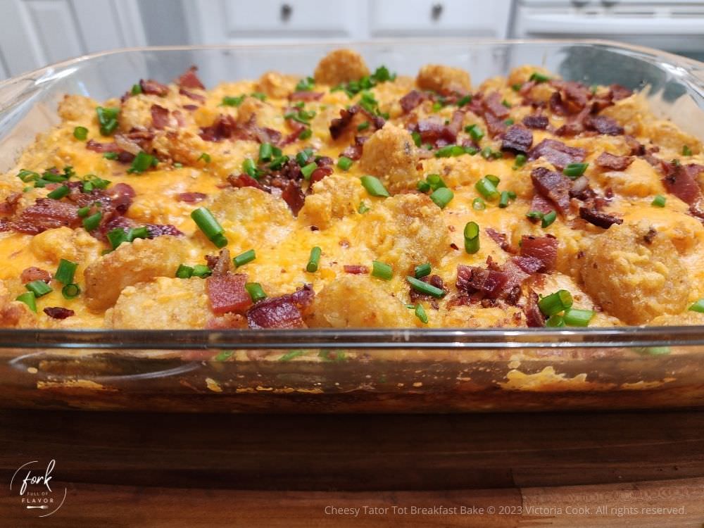 A baking pan of Cheesy Tator Tot Breakfast Bake with bacon crumbles and chives on top