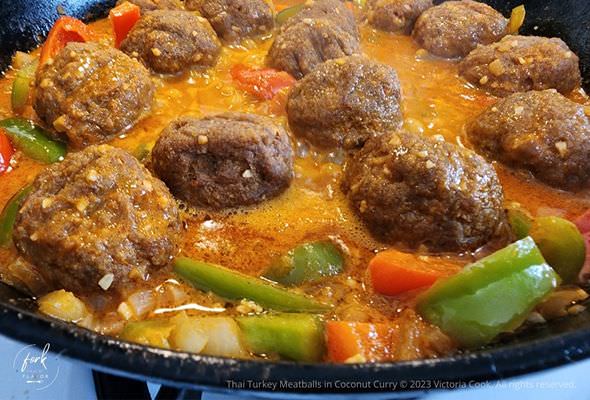 Thai Turkey Meatballs in Coconut Curry cooking in a cast iron pan