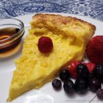 German Pancake plated with fresh berries and a small bowl of syrup