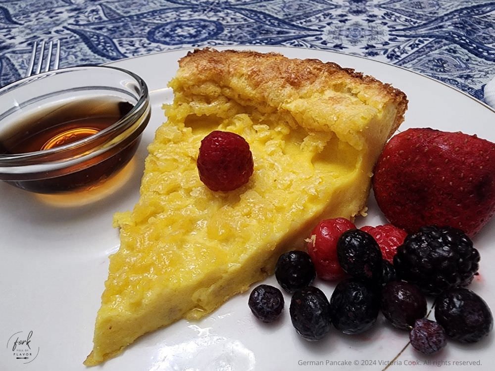 German Pancake plated with fresh berries and a small bowl of syrup