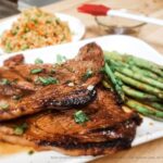 Asian-Inspired Honey Glazed Grilled Pork Steak plated with grilled asparagus and cauliflower fried rice