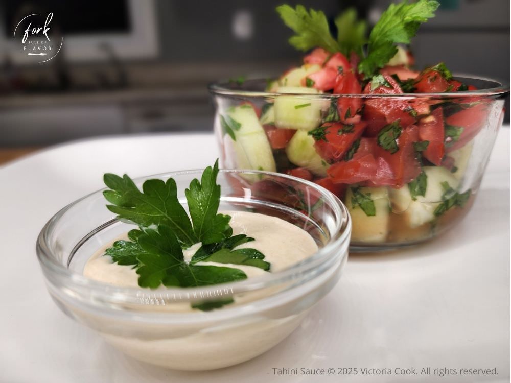Tahini Sauce - Hero Tahini sauce in a bowl with a small salad of tomatoes, cucumbers, and parsley tossed in the tahini sauce