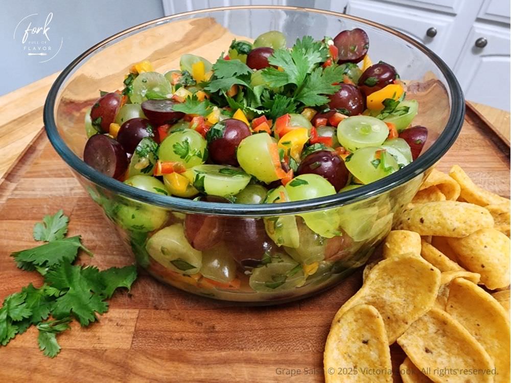 Grape Salsa - Hero A bright bowl of green and purple grapes made into grape salsa garnished with cilantro and served with corn chips.