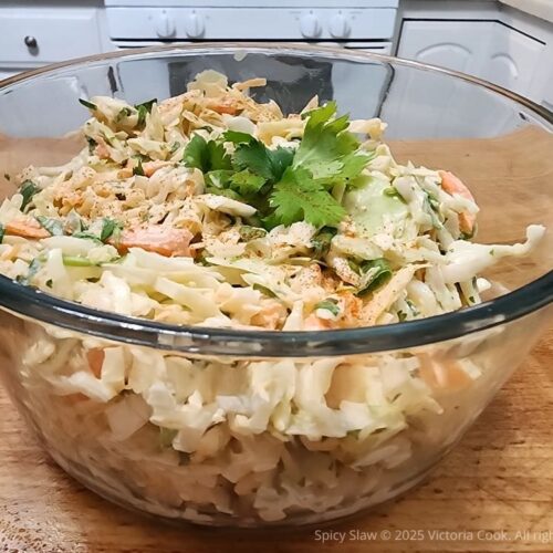 A bowl of spicy slaw topped with a sprig of cilantro.