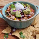 A hearty bowl of taco soup with pinto and black beans, and topped with avocado, cilantro, and sour cream.