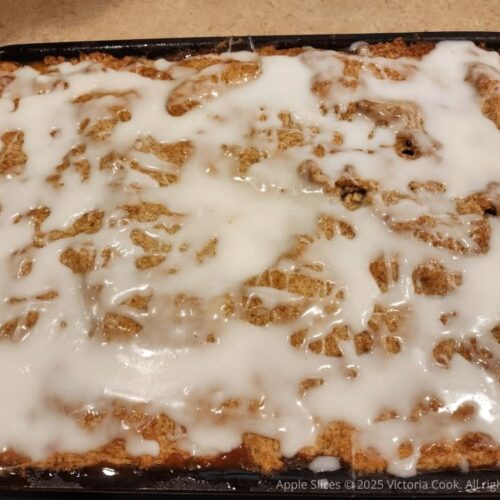 A pan of baked and frosted apple slices.