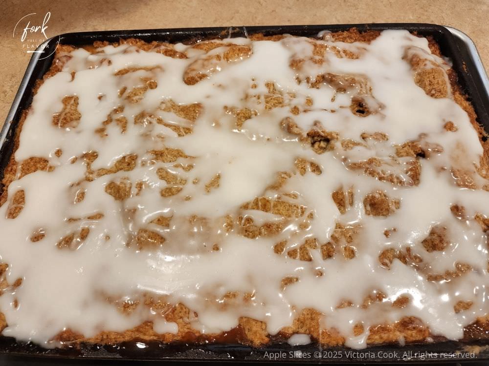 A pan of baked and frosted apple slices.