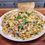A plate of Mexican street corn salad ready for dipping into with taco chips