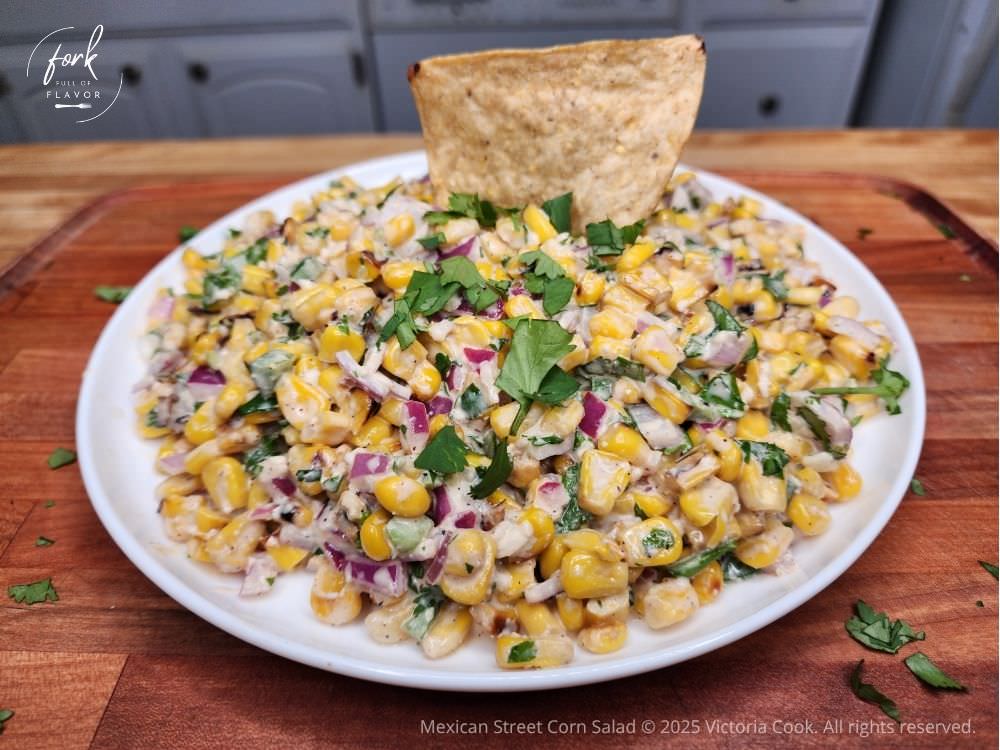 A plate of Mexican street corn salad ready for dipping into with taco chips